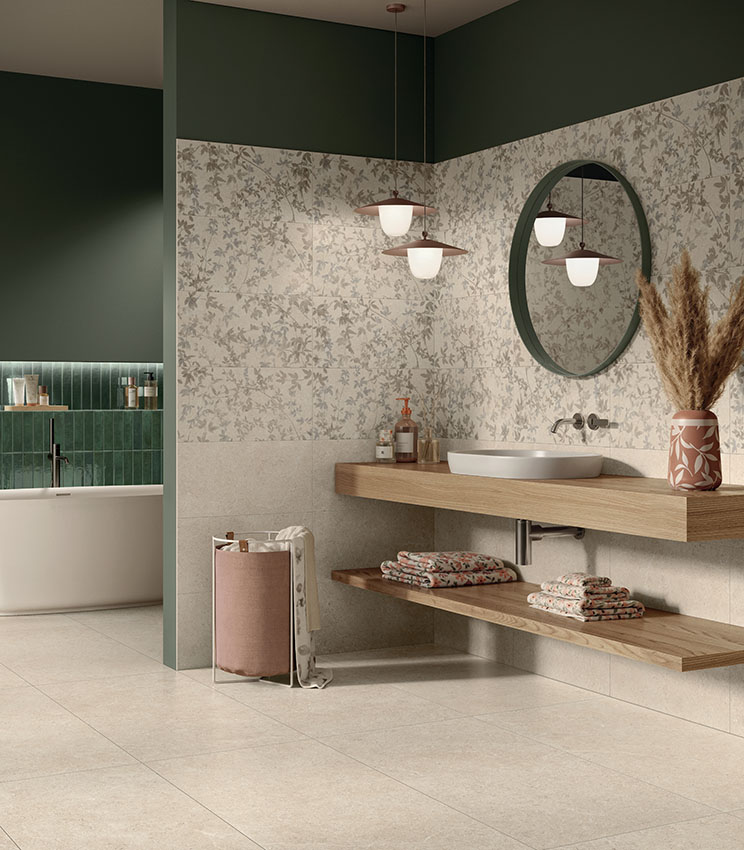 Contemporary bathroom featuring surfaces from the Surround Sketch, Sketch Impressions, Sketch Soft and Workshop Jade collections, with floral wall coverings in neutral tones, dark green walls, a white washbasin on a wooden shelf, a round mirror and a freestanding bathtub visible in the background.
