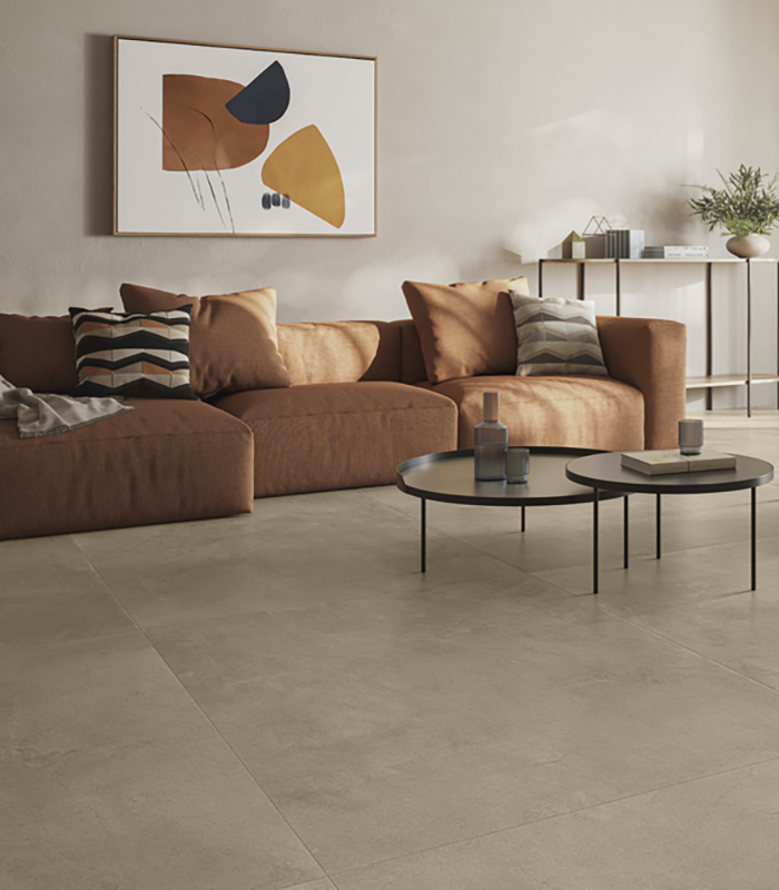 Modern living room with warm, earthy tones, featuring French doors opening onto a terrace and sand-colored concrete-effect porcelain stoneware flooring.