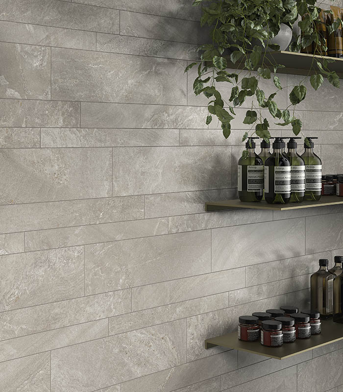 Vista ravvicinata di parete con mensole espositive e rivestimento in listelli multiformato di gres porcellanato effetto pietra di colore