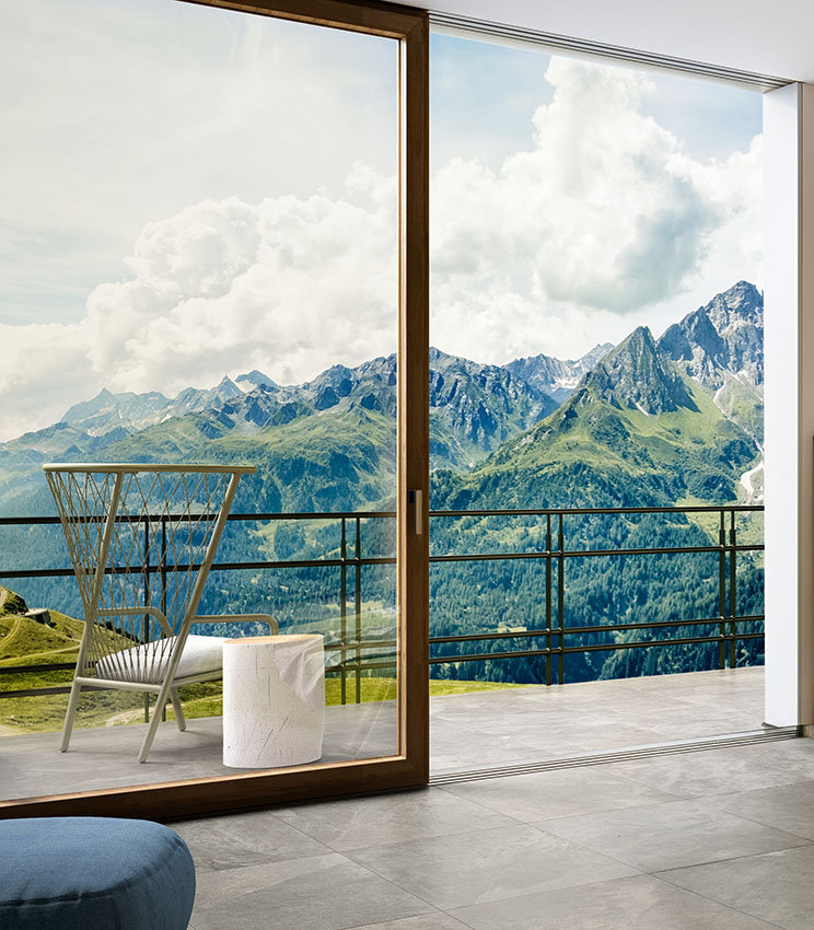 View of the floor of the outdoor paving and French window of a bedroom. Matching outdoor and indoor flooring in gray stone-effect porcelain stoneware.