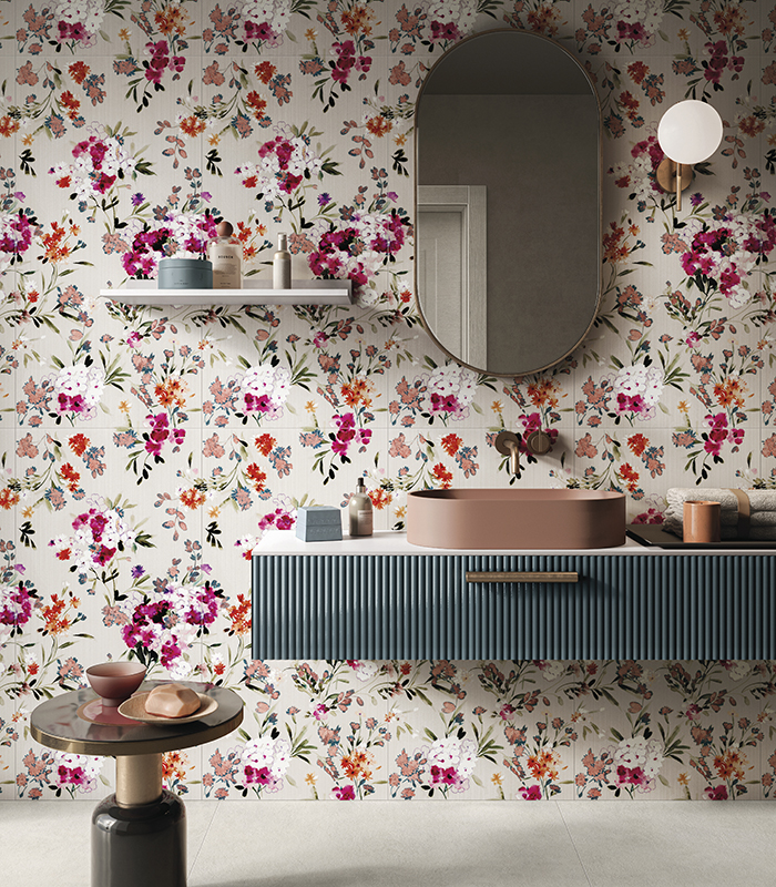 Frontal view of the washbasin wall in a bathroom with light-coloured concrete-effect porcelain stoneware flooring and thin porcelain stoneware wallpaper-effect slabs featuring a floral pattern.
