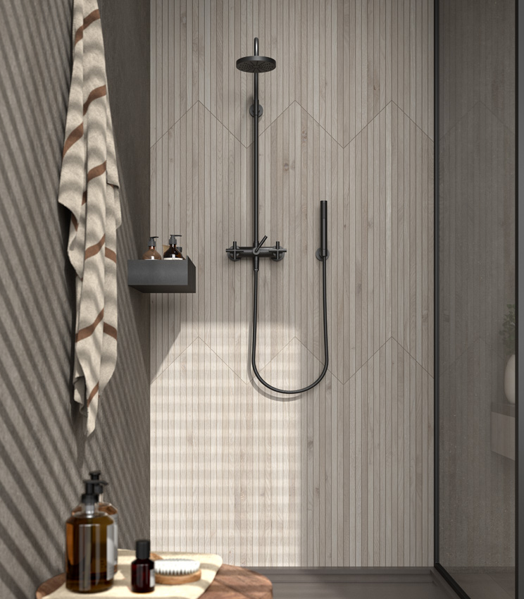 Front view of a shower corner with the fixture wall clad in thin light-coloured wood-effect porcelain stoneware rods, contrasting with the dark adjacent wall and shower tray.