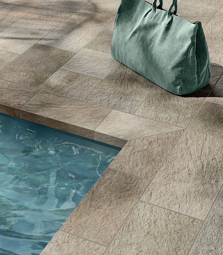 Detail of a pool edge clad in stone-effect porcelain stoneware, featuring a textured surface and natural tones for an elegant and durable result.